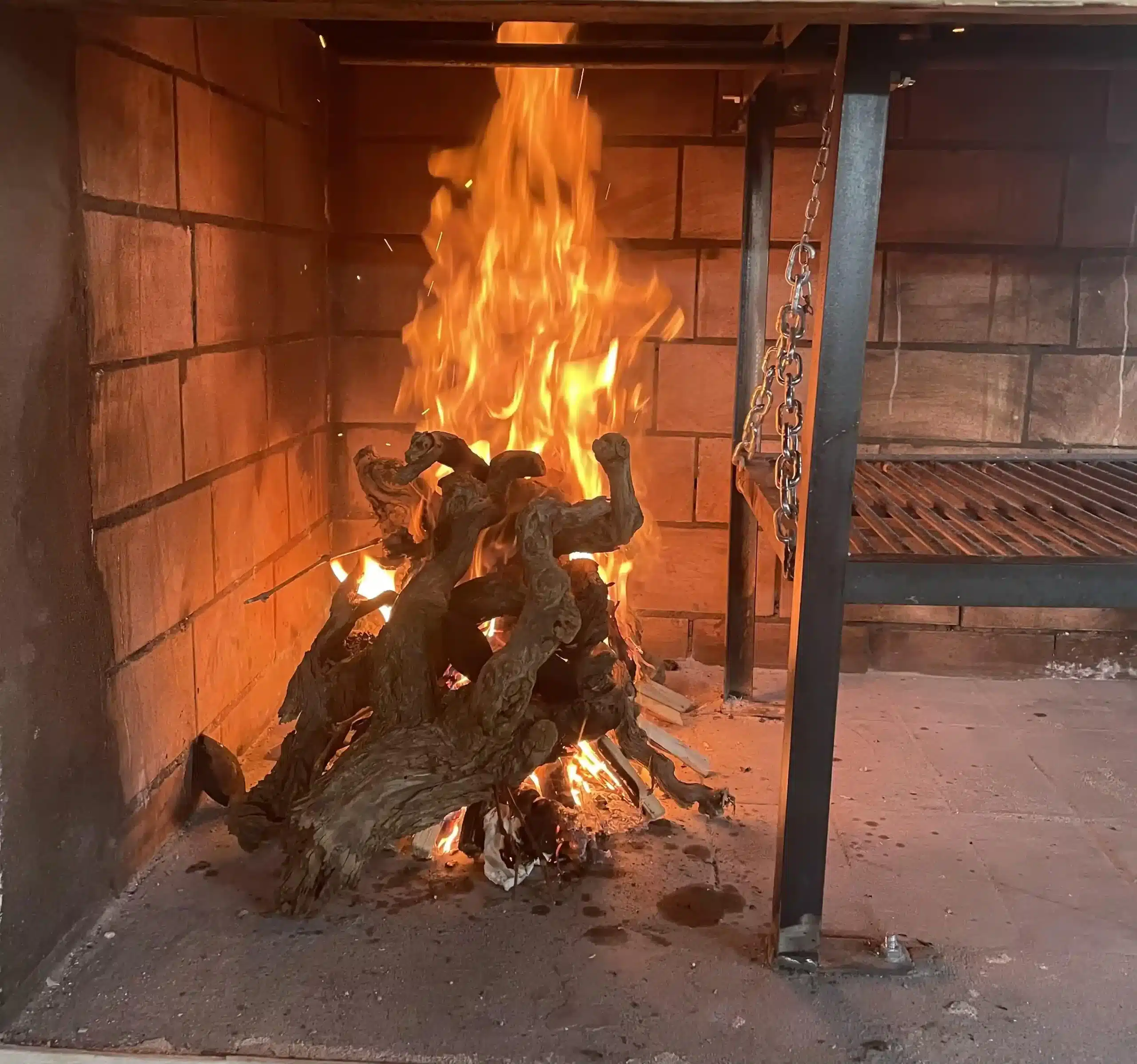Parrilla encendida en el Asador Los Toneles, lista para asar.